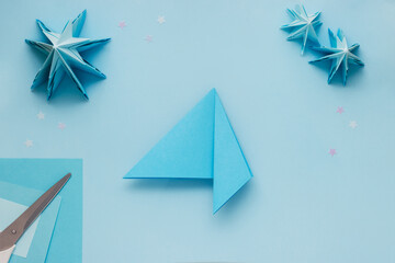 Simple origami 3D Christmas tree made from blue paper. Step by step instruction, step 13. Fold the...
