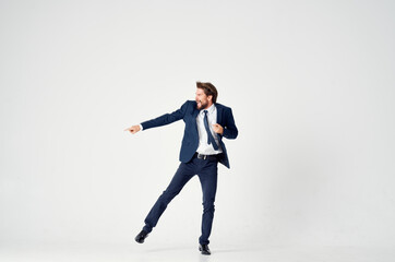 Energetic business man in a blue suit jumps up on a light background success