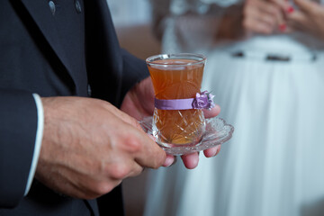 Filtered tea for engagement. Close up of delicious red Azerbaijan tea with traditional pear shaped glass in the man hand . The groom was holding a pear in a cup of tea.