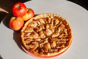 Homemade apple tart on a dish and three apples