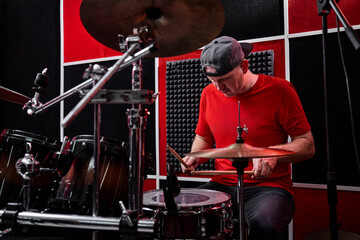 Fototapeta na wymiar Modern professional drummer plays drums at a rehearsal base, red and black recording studio