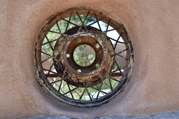 Spoked wheel in a Adobe wall in Santa Fe, New Mexico is a unique abstract artistic touch. A circle in a circle and a window to the world.
