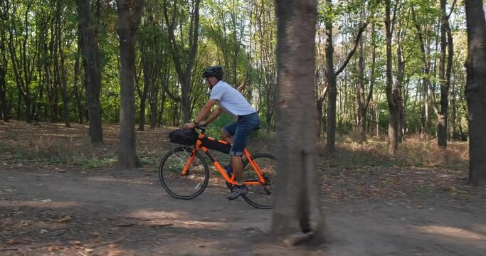 Young male commuter ride on bicycle with halmet in the summer park