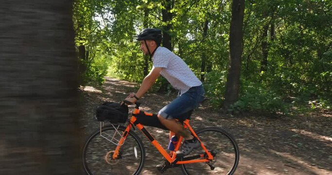 Young male commuter ride on bicycle with halmet in the summer park