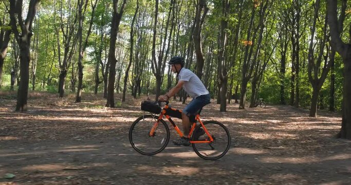 Young male commuter ride on bicycle with halmet in the summer park