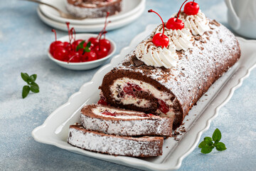 Black forest chocolate swiss roll willed with cherry and whipped cream filling, sliced on a plate
