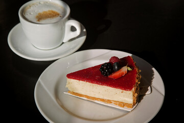 vanilla cheesecake with berries with a cup of cappuccino on the background. 