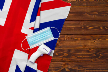 Fototapeta na wymiar Medical face mask and contactless thermometer on British flag