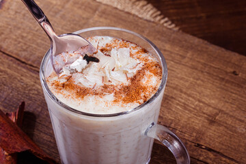 Creamy rice pudding in a glass and spoon stirring the candy, on rustic wooden background..Slightly defocused background.