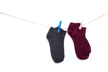 several colored socks hanging on a rope with clothespins isolated on white background