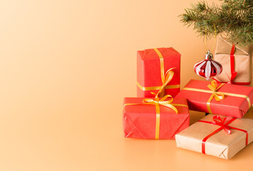 Gifts in beautiful red boxes with gold ribbons under a Christmas tree decorated with glass toys. Holiday. New year and Christmas. Copy space