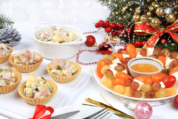 Fototapeta na wymiar Christmas new year dishes, traditional festive salad olivier and cheese with tomatoes, grapes and honey with fir branches and cones and decorations, dish design idea, selective focus,