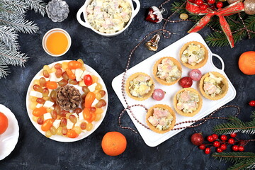 Christmas new year dishes, traditional festive salad olivier and cheese with tomatoes, grapes and honey with fir branches and cones and decorations, dish design idea, selective focus,