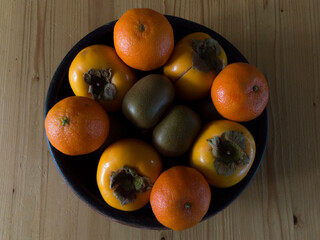 Kiwis, kakis and tangerines in a bowl