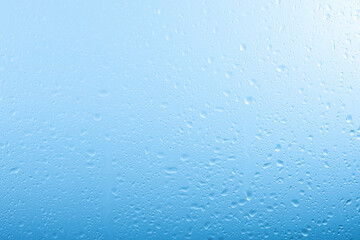 Raindrops on glass window over grey and blue sky