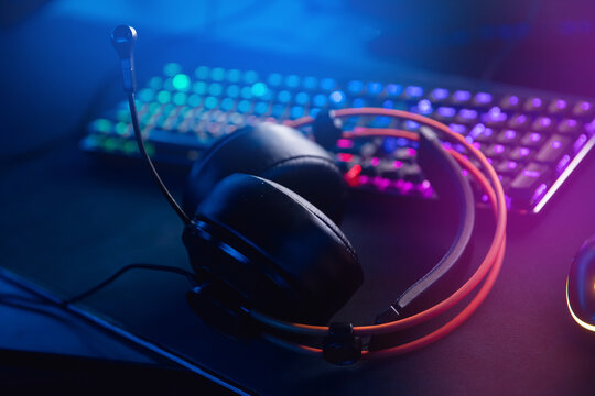 Professional headphones with microphone for video games and cyber sports gaming in neon color blur background