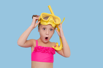 Little child girl in scuba mask and snorkel on blue background. Funny face, wow emotions. Summer...