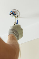 A worker is installing an LED spotlight on the ceiling.