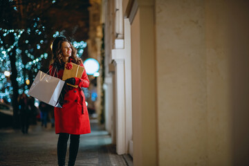 happy woman looking at shop window outdoors in city in evening