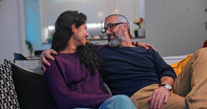Senior father kissing daughter while sitting on sofa at home