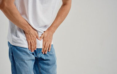 man experiencing pain below the belt in the groin and jeans t-shirt model