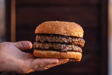Cropped view of person holding tasty cheeseburger.