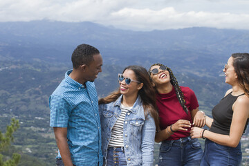 group of four young Latin American adventurers friends three women one man outdoors talking...
