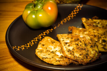Vegetarian food - celery tuber slices fried in batter in a ceramic plate on a wooden table, close up