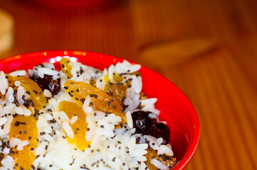 handmade preparation of treats for traditional Orthodox Christmas - rice pudding with fruits, cranberries, honey, nuts, Church candles