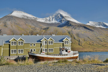 Fototapeta na wymiar Fishing boat next to classic nordic harbor building, Iceland