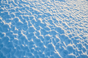 Beautiful winter background with snowy ground. Natural snow texture. Wind sculpted patterns on snow surface.
