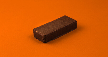 Sweets food concept, chocolate waffle bar on orange background, copy space, banner