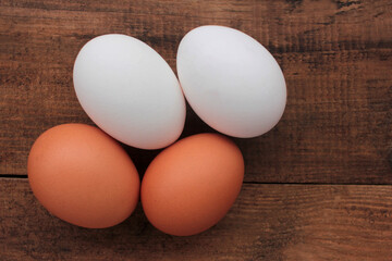 Eggs on wooden table. Overhead view of white and brown chicken eggs on wood background.