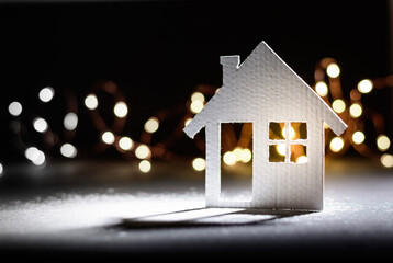 Small cardboard house on a dark winter background.