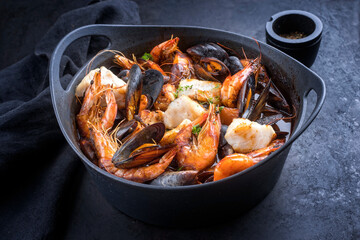 Traditional French seafood bouillabaisse with fish, king prawns and mussels in red wine sauce as...
