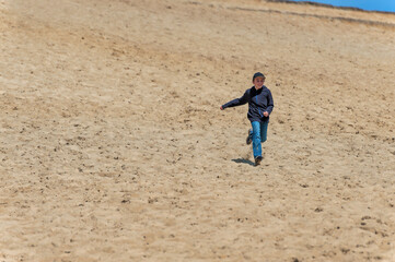 Boy plays on large sand dune hill at Pacific City on Oregon Coast