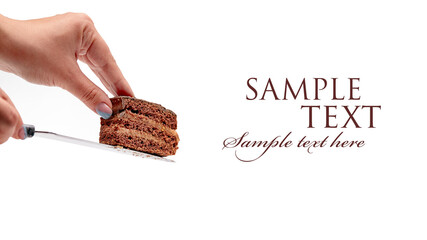 Women's hands hold a piece of layered chocolate cake on a knife on an isolated white background
