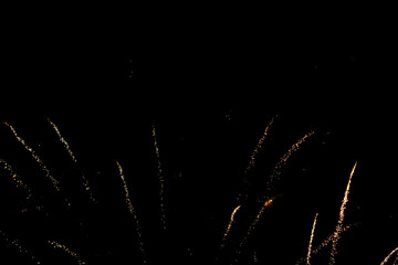 Sparkling golden fireworks spurs on the black background at night. Wallpaper with copy space for...