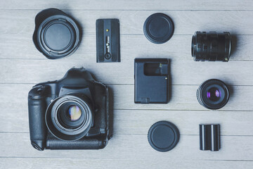 Flat lay with different photoaccessories on boards: camera, lenses, battery, charger, synchronizer, and lens covers