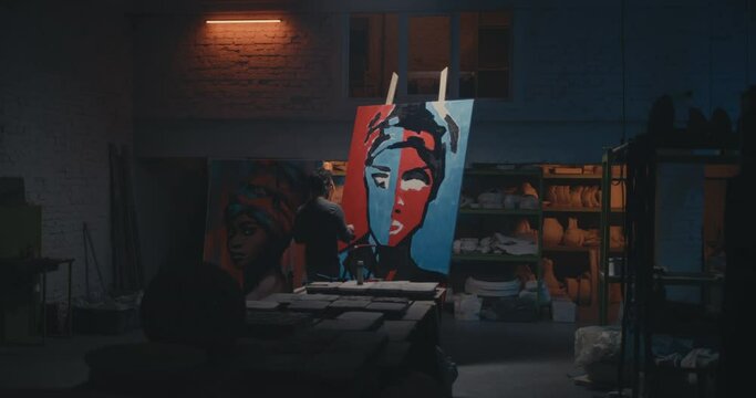 Anonymous artist painting portrait in dark studio