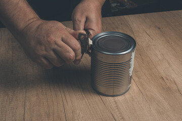 Opening tin can isolated on wooden background. Vintage editing. Concept home working,