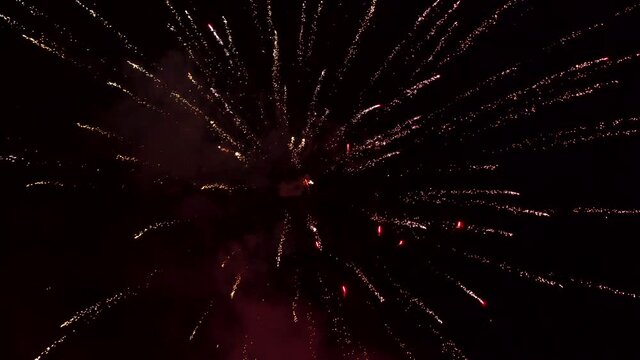 Colorful fireworks emitting sparks. Stock video of fireworks at night. New Years Eve Celebration. Particle Effect, Glowing, Blazing, Twinkling, Glistening.
