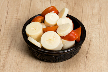 Simple and fresh palm heart or palmetto salad in a black bowl on a wooden table.