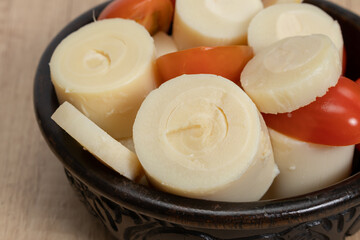 Simple and fresh palm heart or palmetto salad in a black bowl on a wooden table.