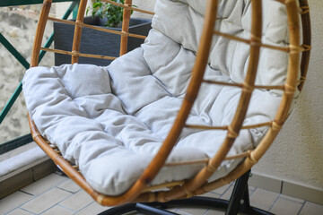 Fototapeta na wymiar Bamboo chair with gray cushion hanging on the balcony