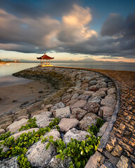 Rocky shore of the Sanur beach surrounded by the sea on a stormy day in Bali, Indonesia