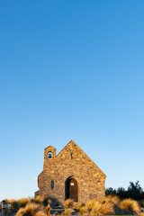 Fototapeta na wymiar Sun sets on stone front of Church of Good Sheppard in Tekapo.