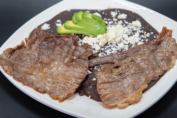 Carne asada steak perfectly prepared on the grill with beans and avocado on the top.