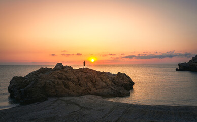 Fototapeta premium Alone person on stone at Paralia Paltsi beach, Magnesia, Greece