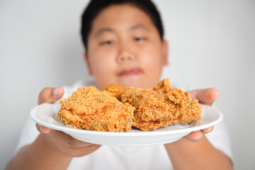 Asian fat boy eats fried chicken Wear a white shirt. Concepts of child health problems Pathogenic...